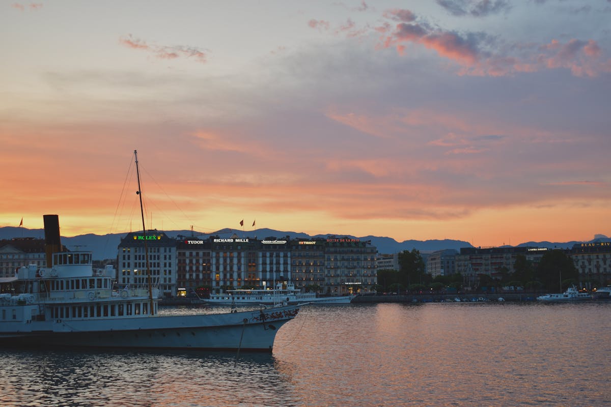 Geneva waterfront skyline at golden sunset with boat on Lake Geneva