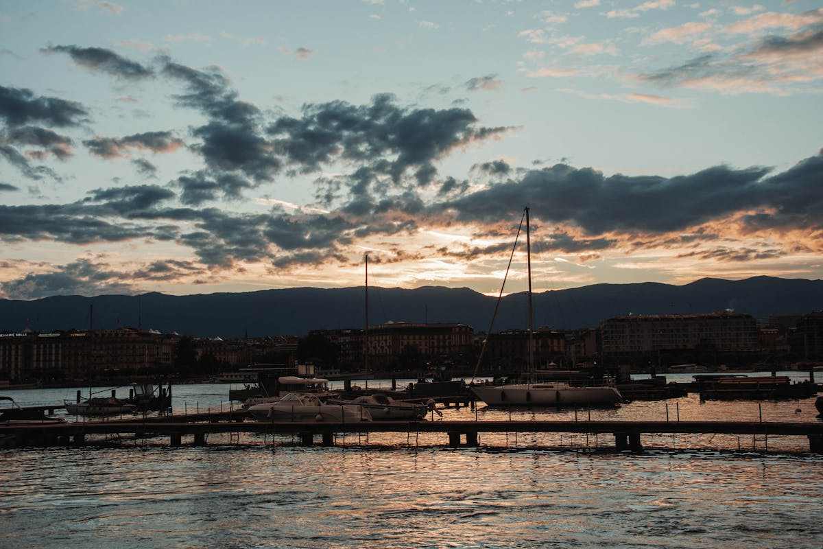 Elegant yachts moored at sunset on Lake Geneva with city skyline view