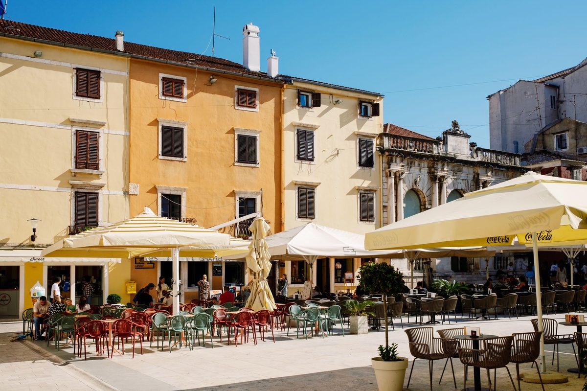 A sunny cafe terrace on a square, like the terraces ringing Place du Marche in Carouge