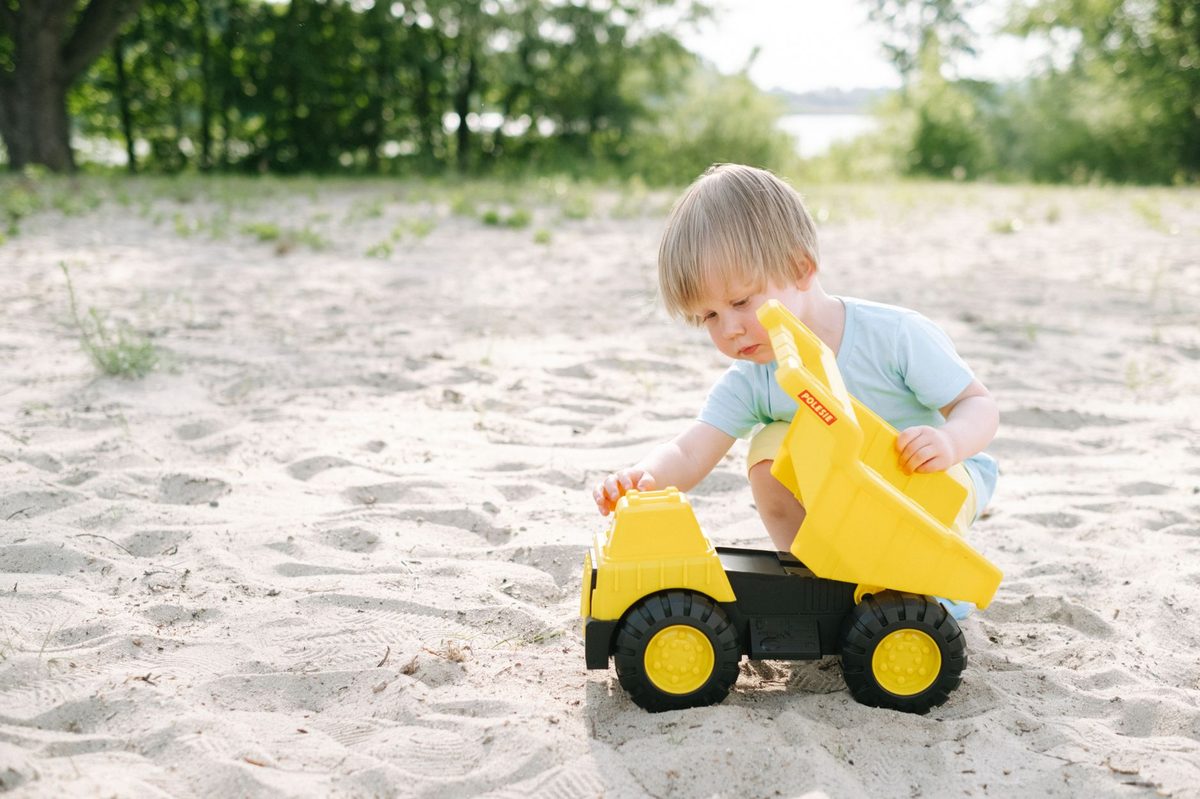 A toddler playing on a small sandy lake beach like Baby Plage in Geneva