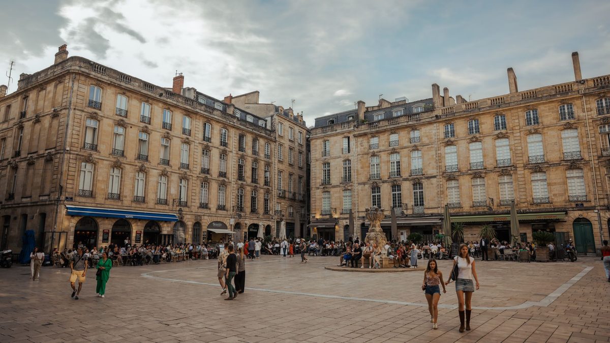A medieval square with cafe terraces and a fountain, like Place du Bourg-de-Four in Geneva Old Town