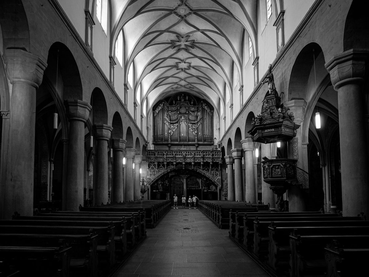 A plain wooden pulpit and stone nave, like the church where Calvin preached during the Geneva Reformation