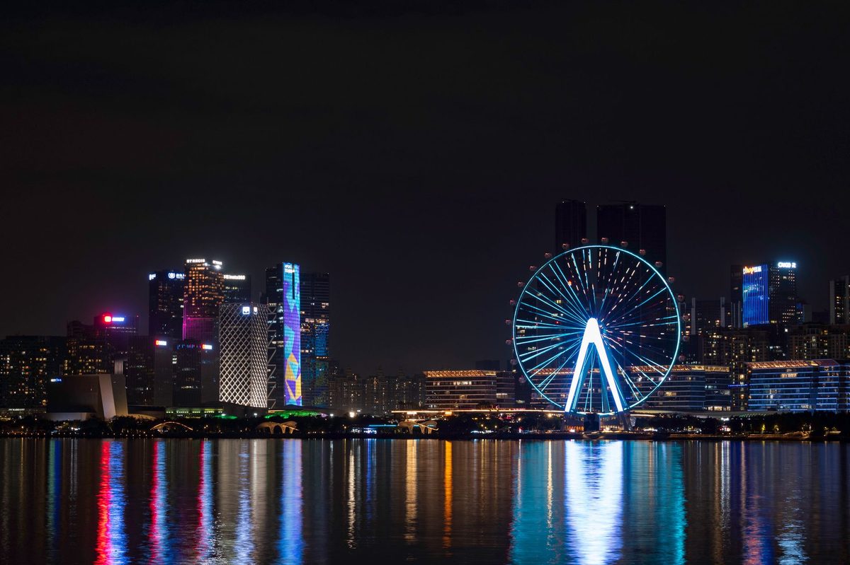 Lit Ferris wheel and fairground rides along Geneva's lakefront in summer