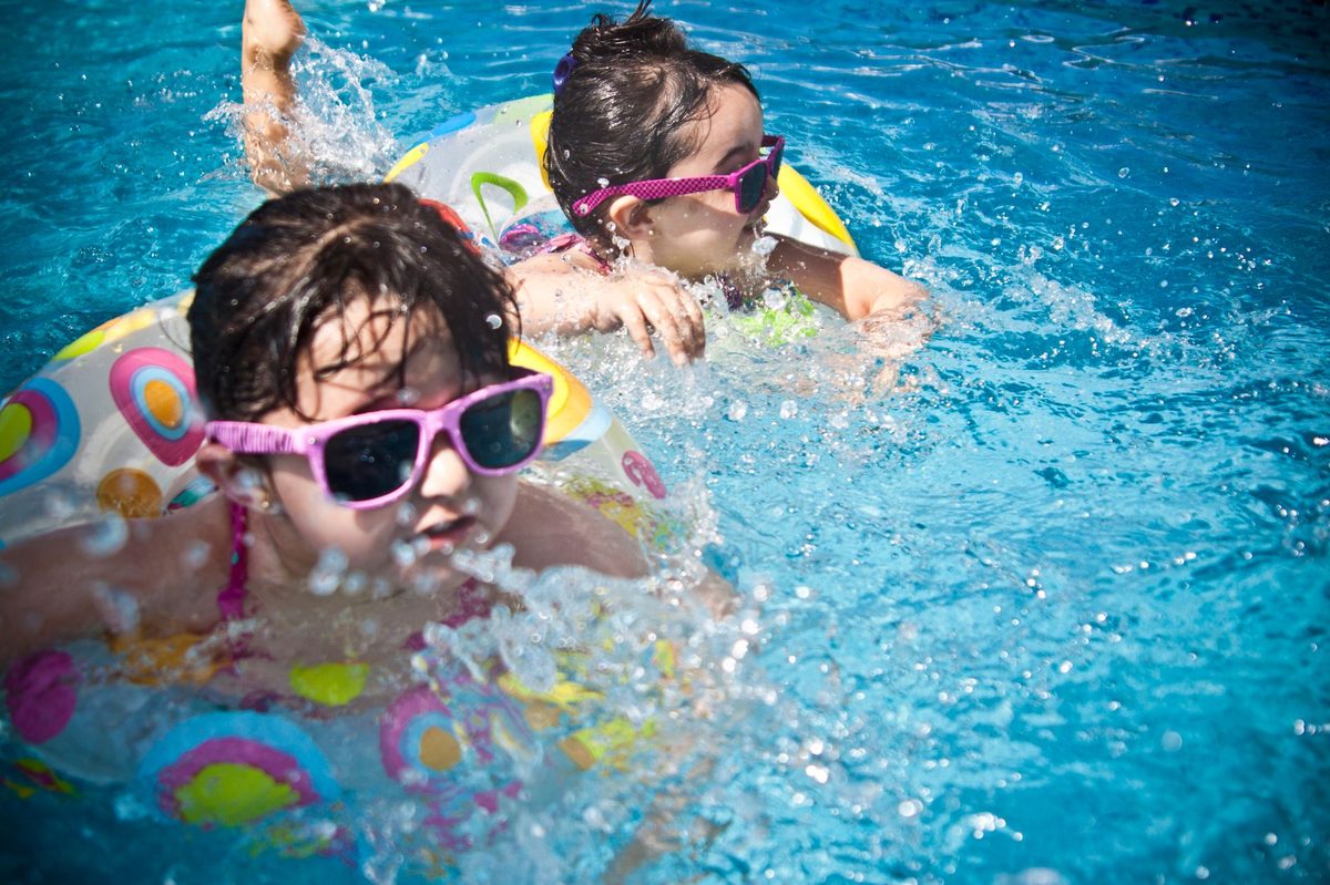 Kids playing at an outdoor pool on a summer day, like Geneve-Plage