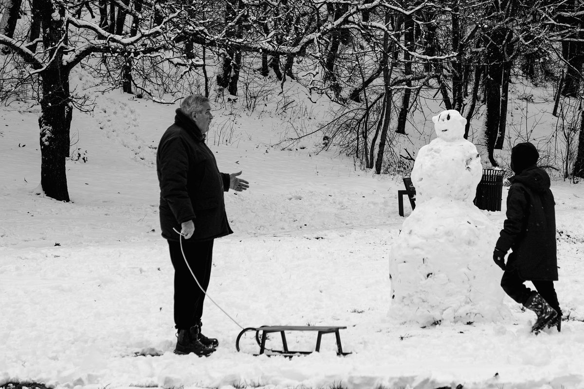 Kids sledging on a snowy slope like Parc Trembley in Geneva in winter