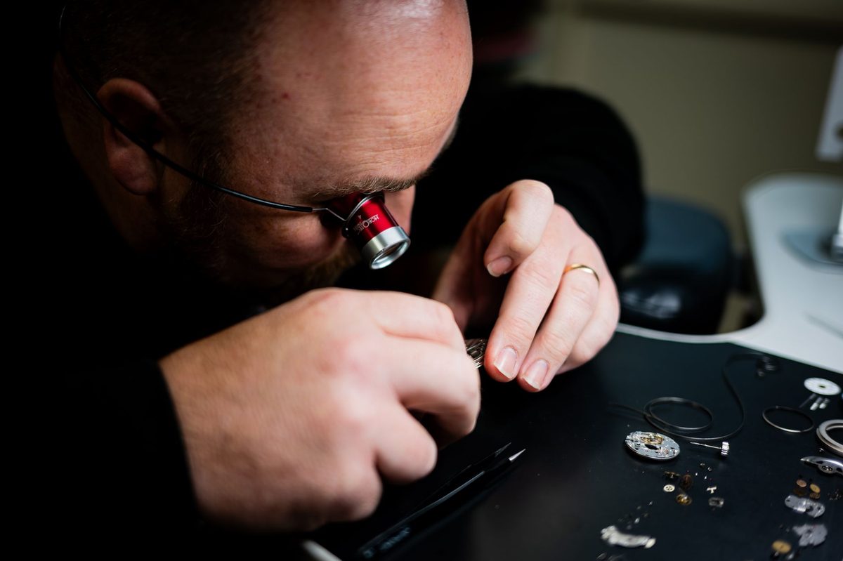 Watchmaker at the bench assembling a mechanical movement, the same craft Geneva has practised since the 1700s