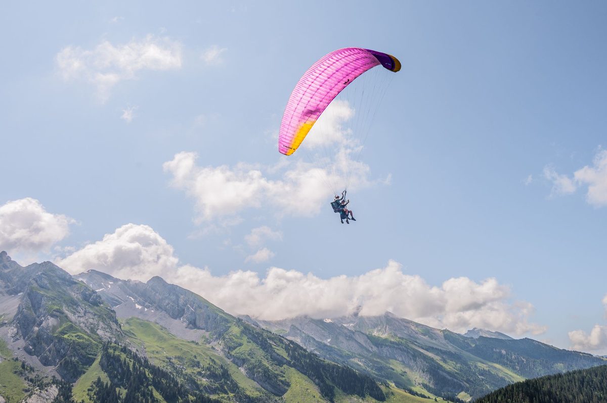 A tandem paraglider flying above the Geneva basin from Mont Saleve