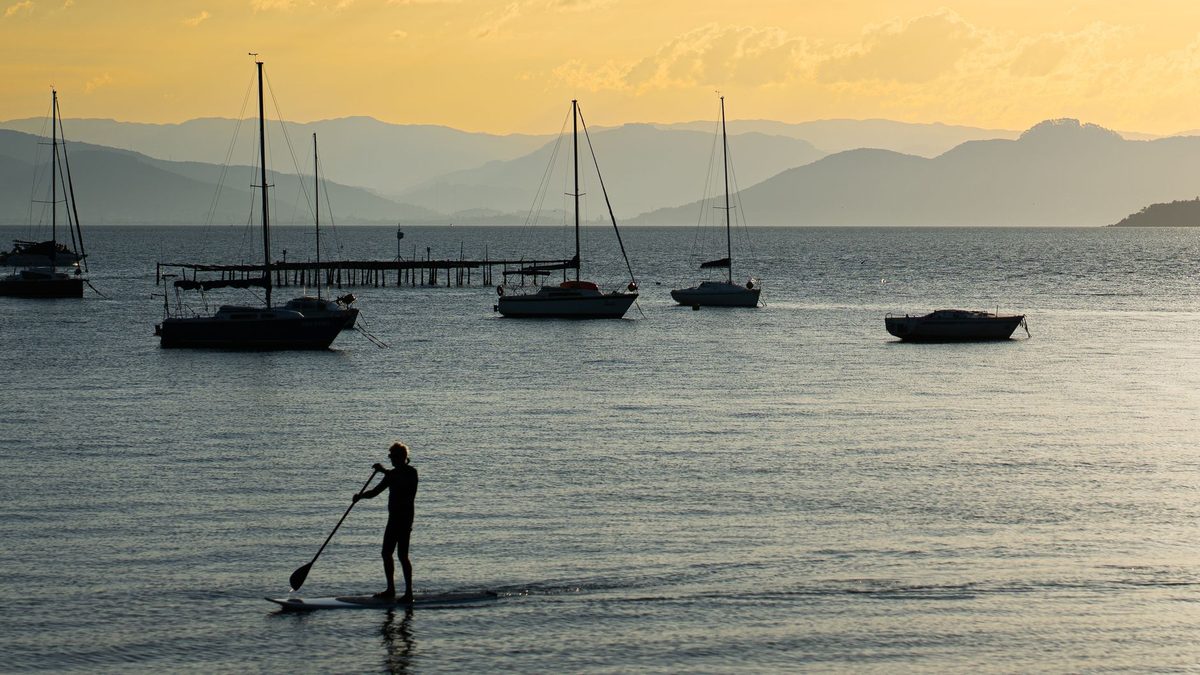 Stand-up paddleboarder on calm Lake Geneva water at dawn near Geneva