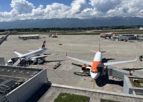 SWISS and easyJet aircraft at their gates at Geneva Airport, seen from the panorama terrace with the Jura mountains behind