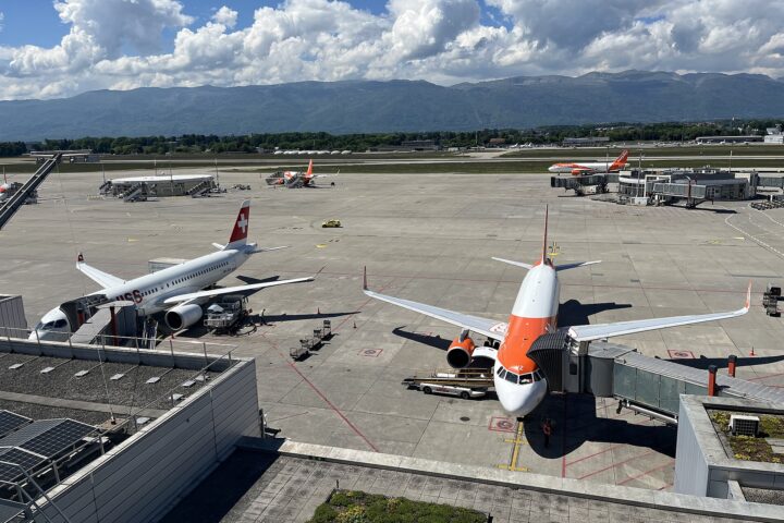 SWISS and easyJet aircraft at their gates at Geneva Airport, seen from the panorama terrace with the Jura mountains behind