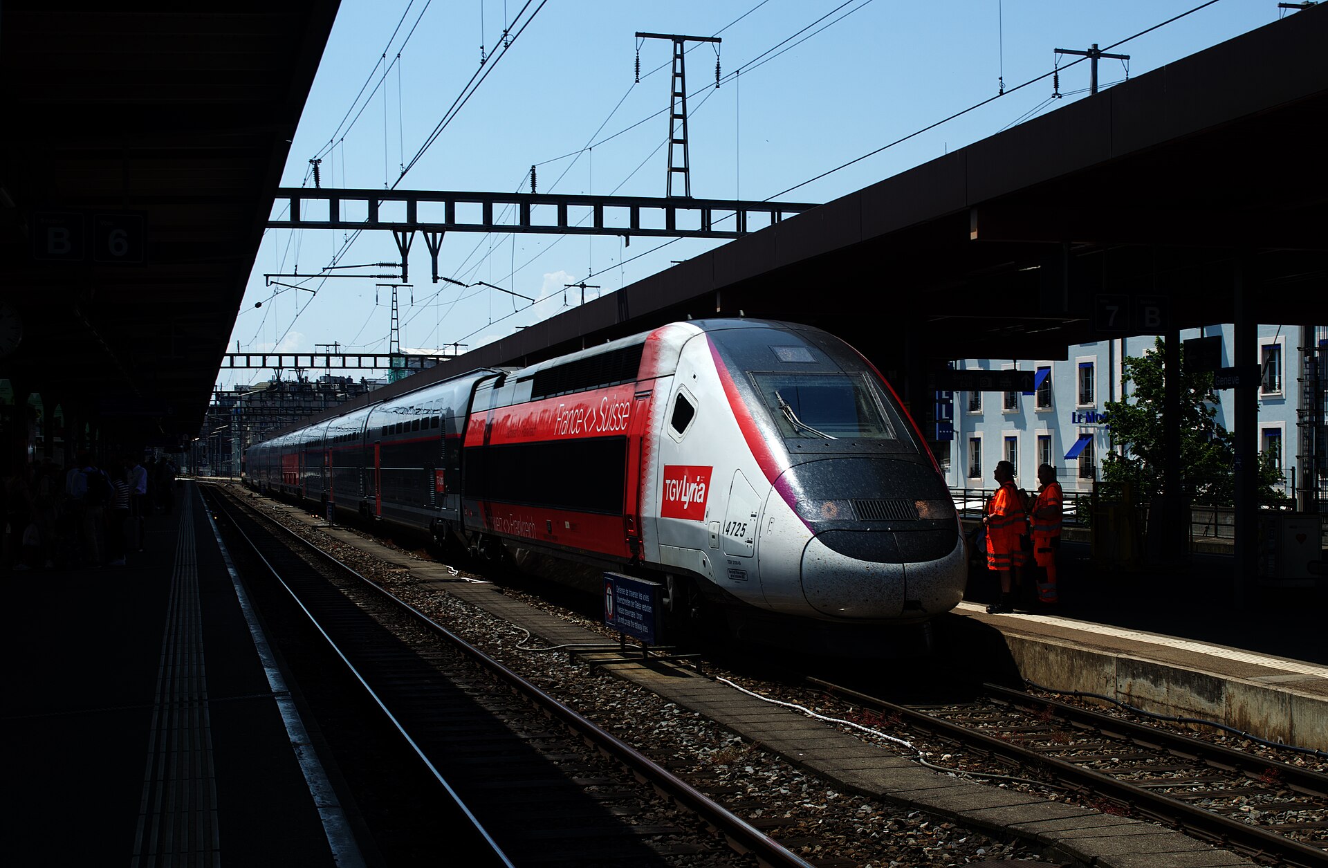 A red and white TGV Lyria high-speed train at a platform in Geneva-Cornavin station