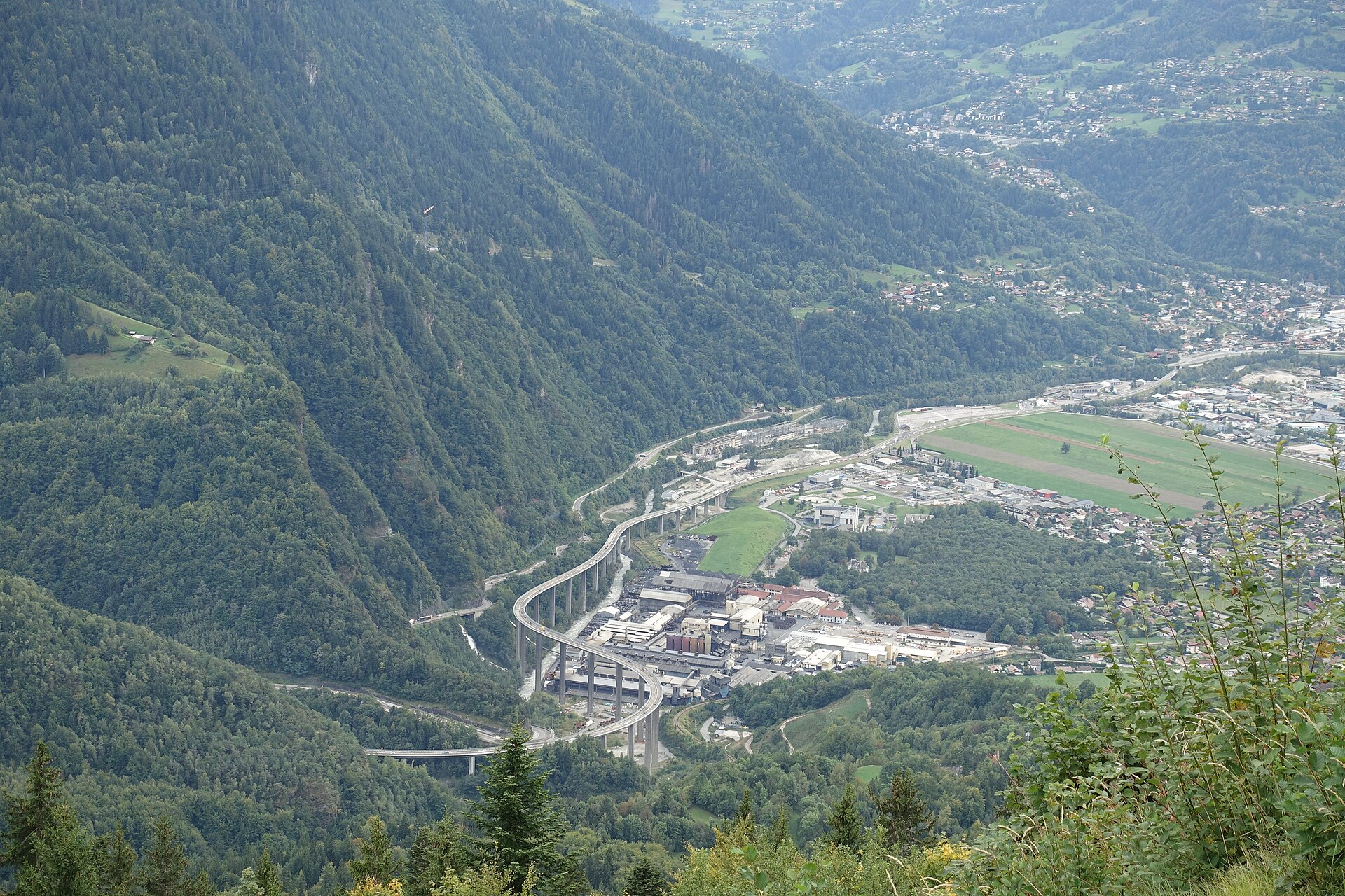 The A40 motorway curving on viaducts through the Arve valley near Passy, seen from the mountainside above