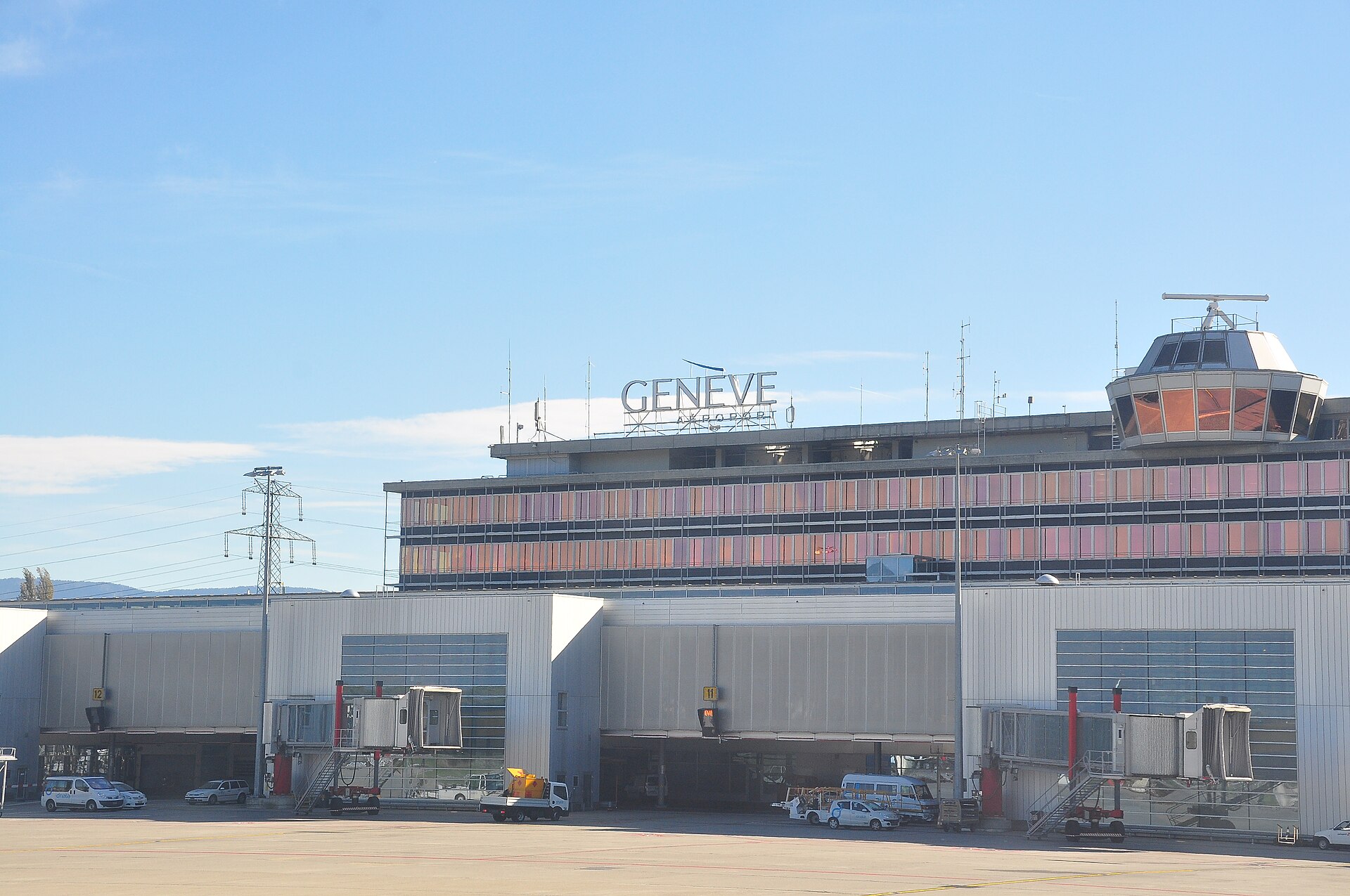 The Geneva Airport terminal seen from the apron, with the Genève Aéroport sign and the control tower