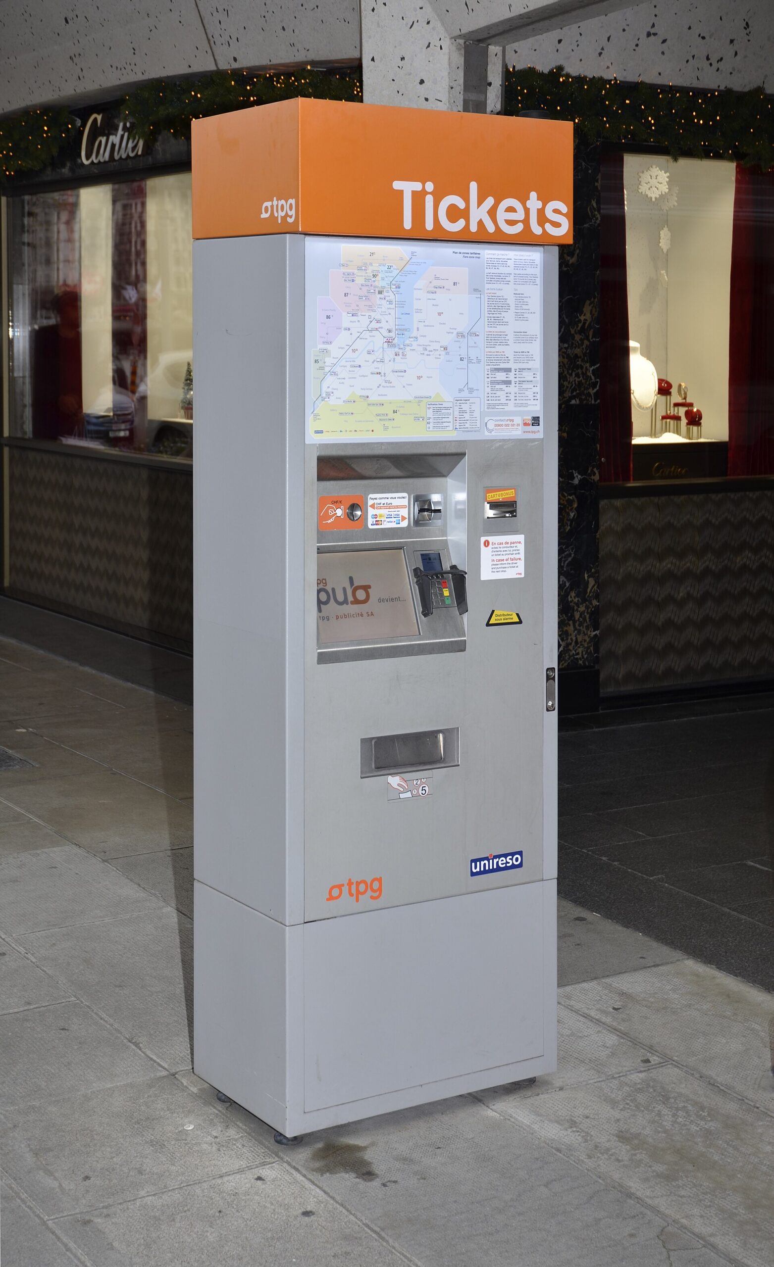 An orange-topped tpg ticket machine on a Geneva pavement, accepting coins and cards