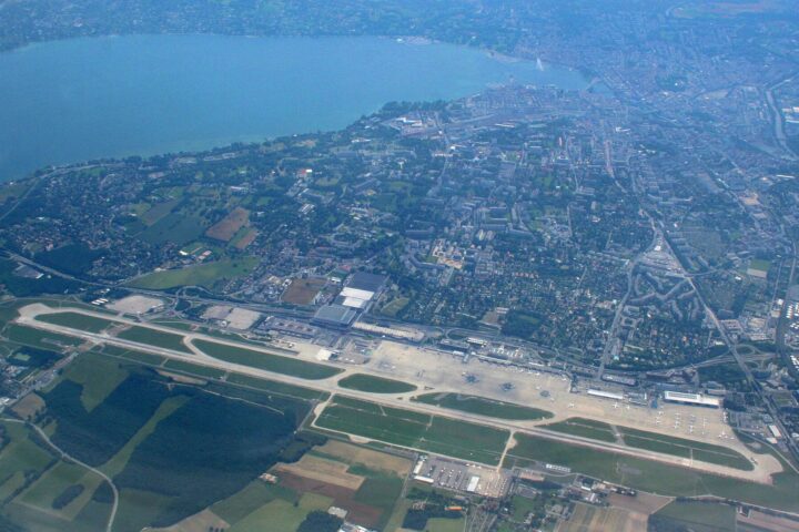 Aerial view of Geneva Airport's single runway with the city and Lake Geneva beyond