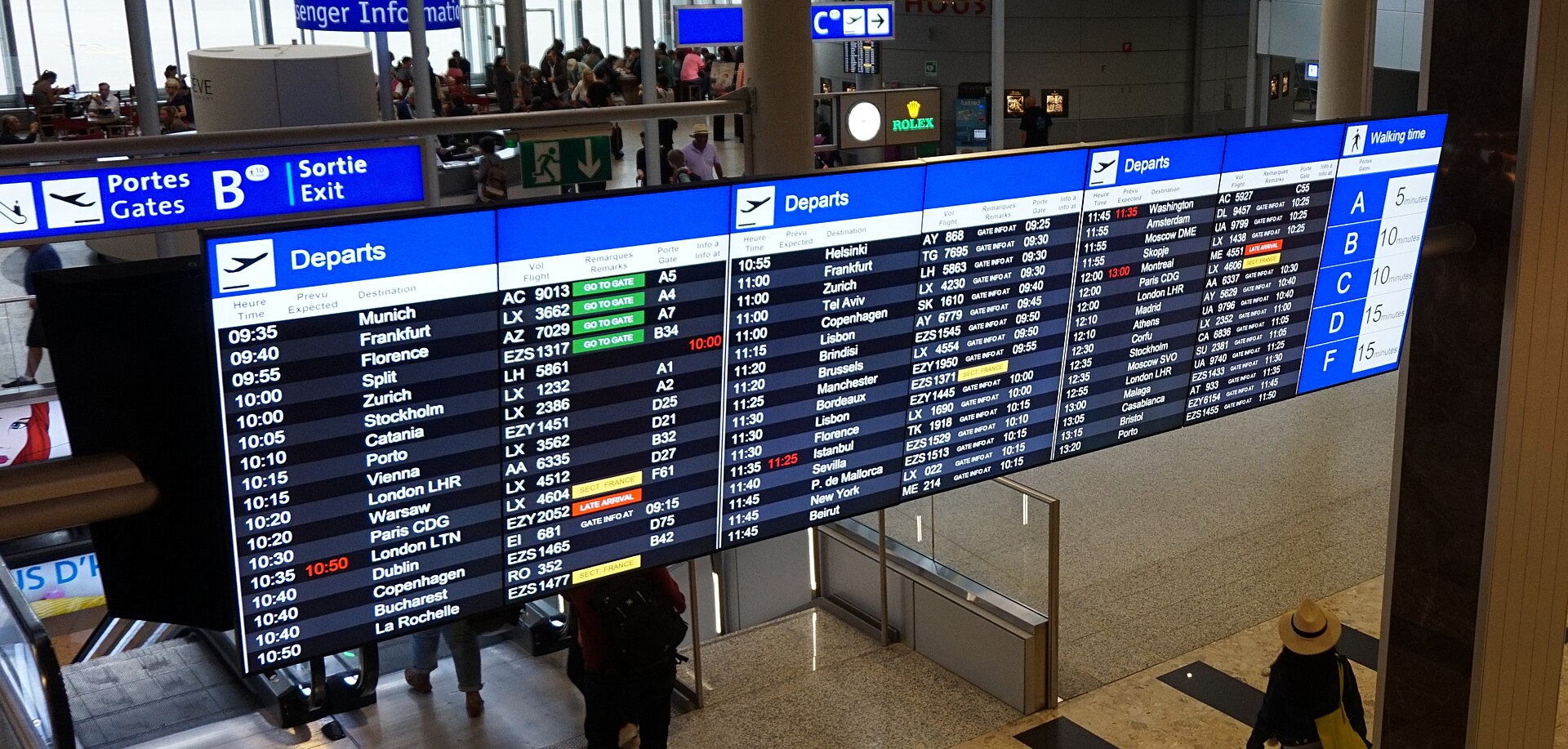 Departure boards at Geneva Airport listing flights, gates and walking times to each pier