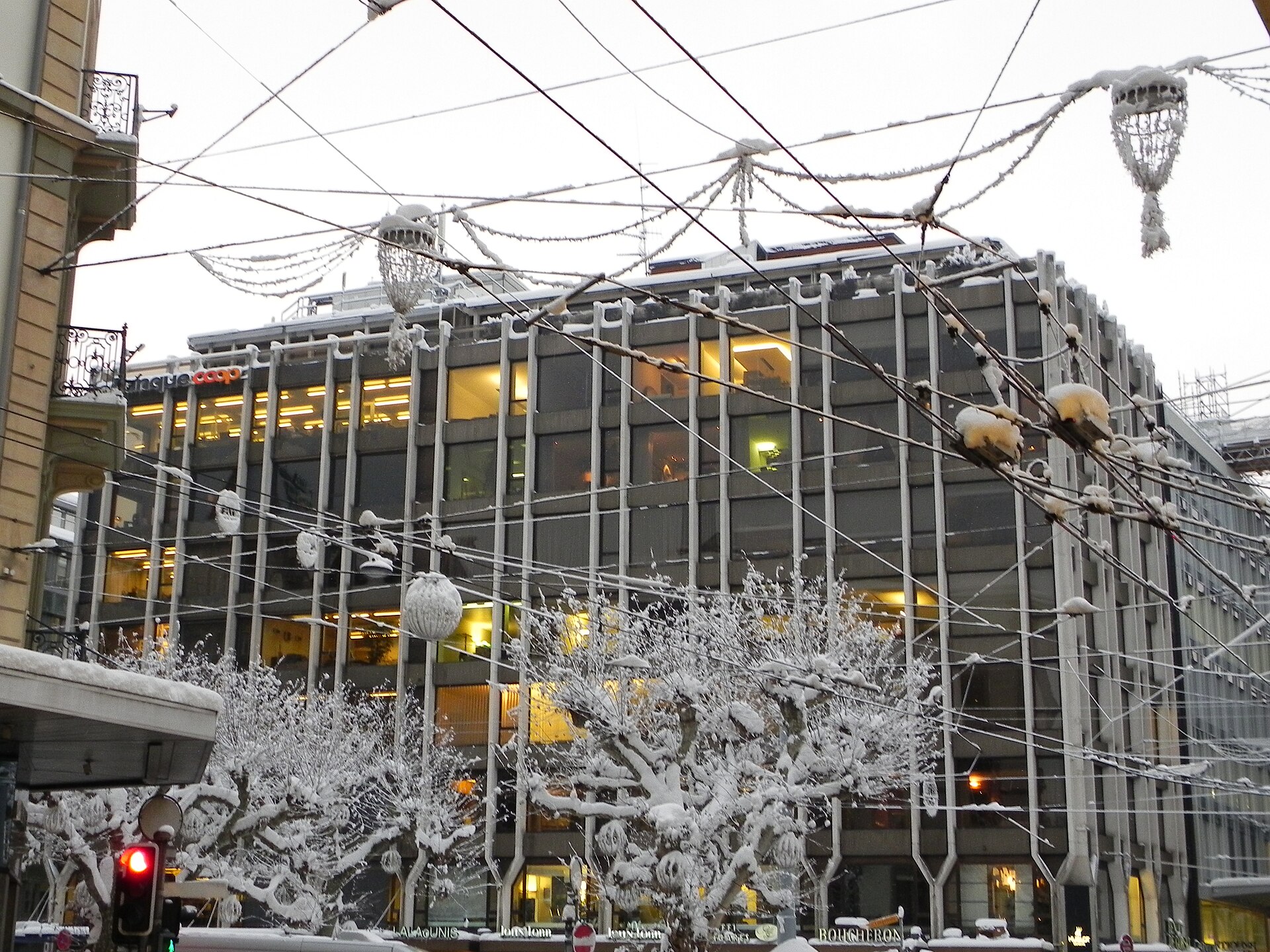 Snow-covered plane trees and Christmas lights above a Geneva shopping street near the Rue du Rhône