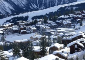 Courchevel 1850 under deep fresh snow, with chalets, the church spire and the pistes rising behind