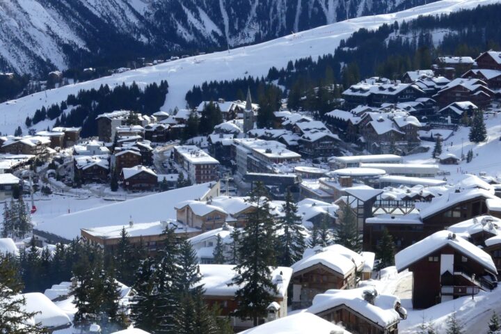 Courchevel 1850 under deep fresh snow, with chalets, the church spire and the pistes rising behind
