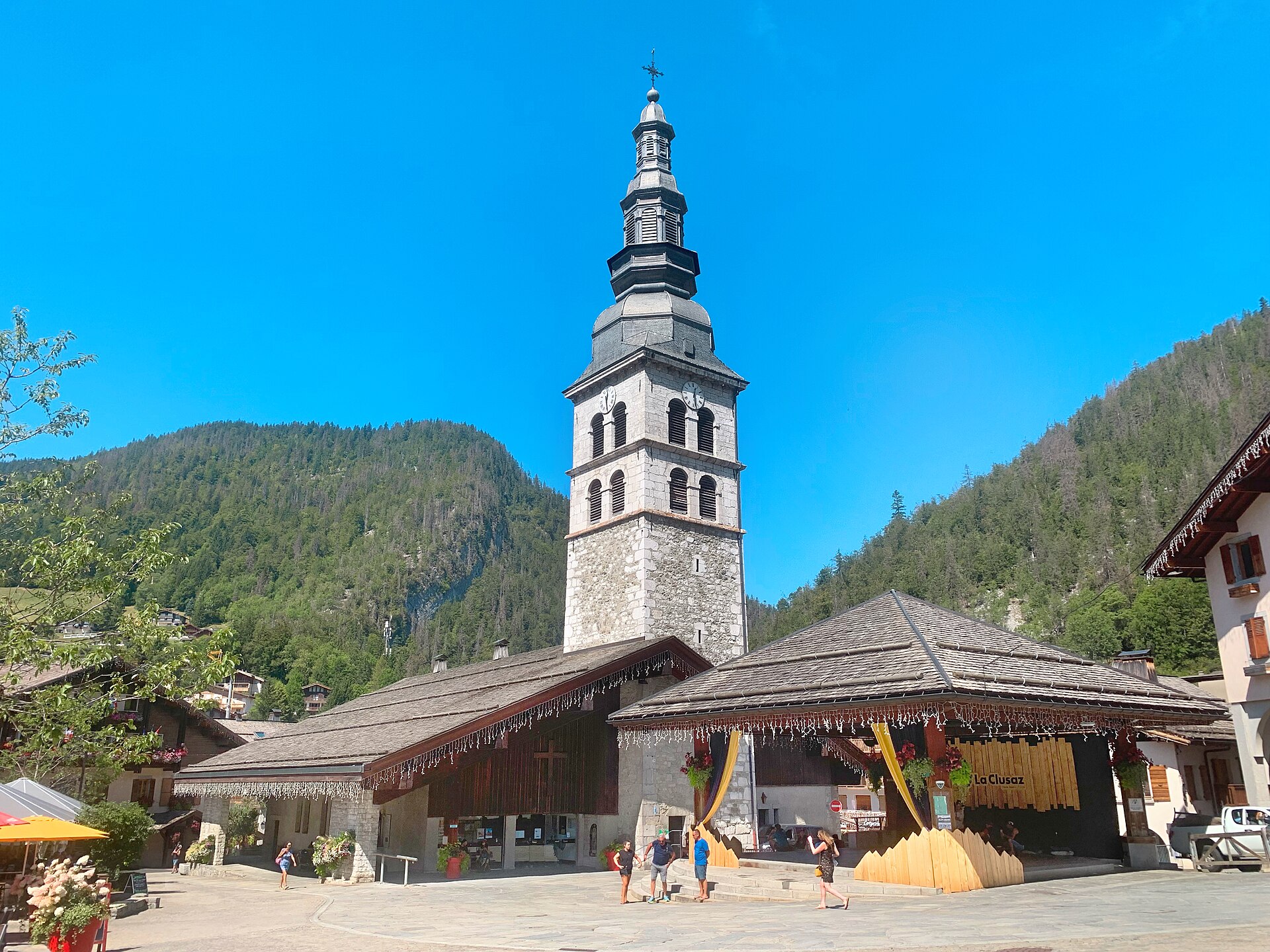 The church of La Clusaz with its tall bell tower beside the village square on a clear day