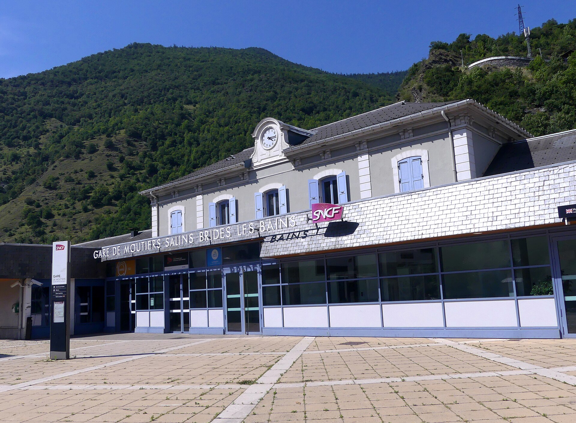 The station building at Moûtiers-Salins-Brides-les-Bains with its SNCF signage and empty forecourt in summer