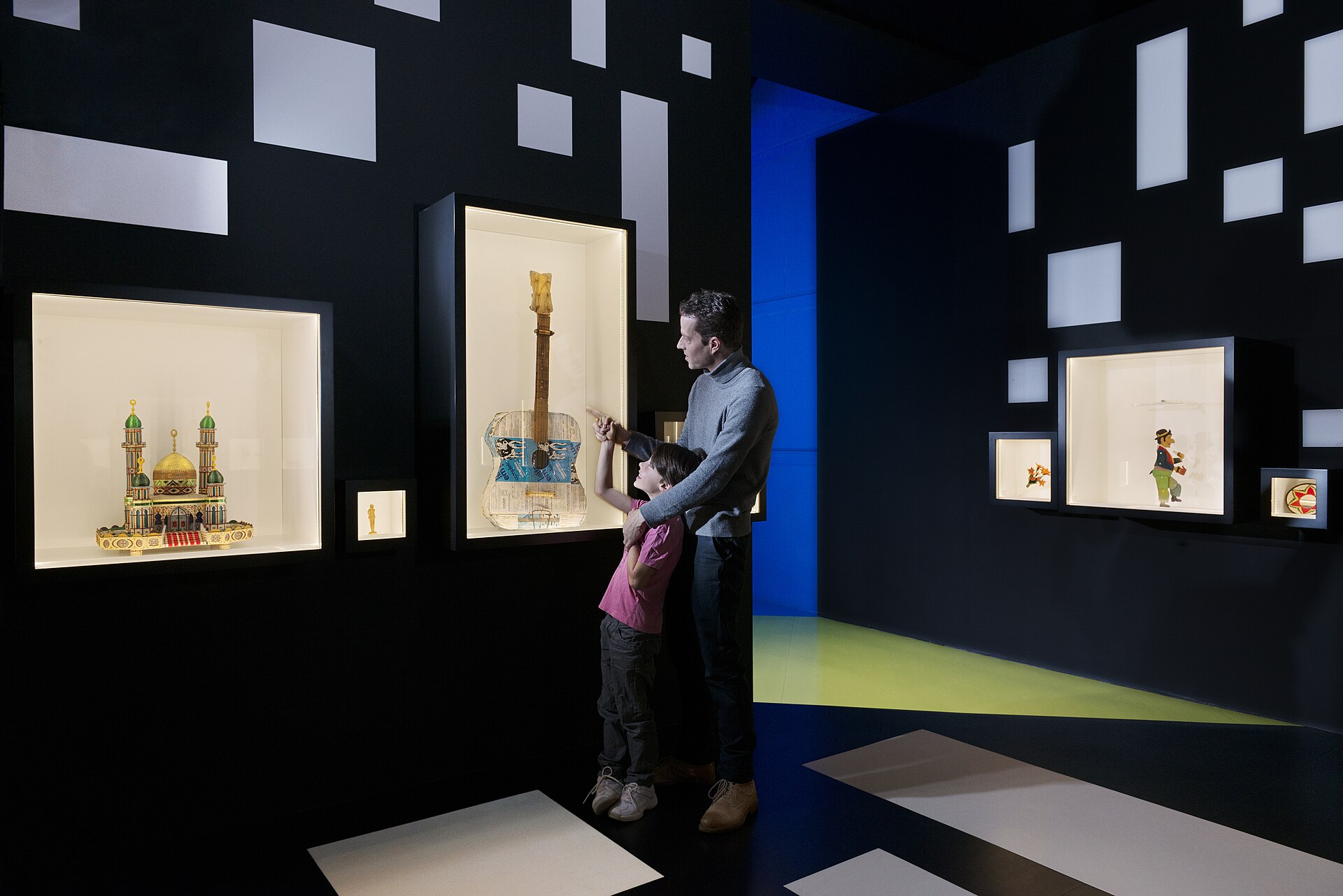 An adult and child examine objects made by prisoners in illuminated cases at Geneva's International Red Cross and Red Crescent Museum.