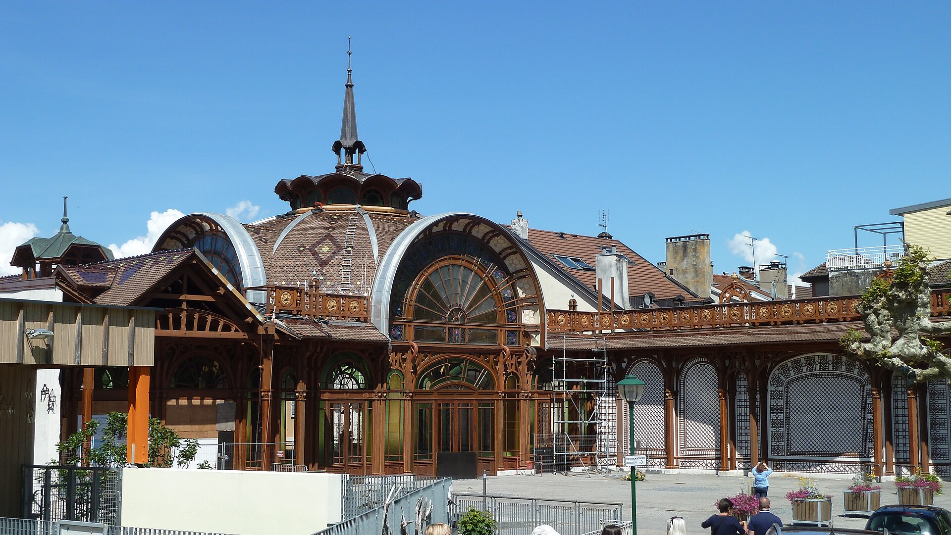 Curved glass gables and a patterned dome crown the former Buvette Cachat in Evian-les-Bains, with scaffolding beside its entrance.
