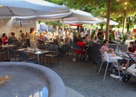 Diners fill Café Papon's shaded Geneva terrace beside a stone fountain during the Fete de la musique.