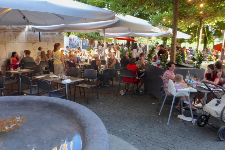 Diners fill Café Papon's shaded Geneva terrace beside a stone fountain during the Fete de la musique.
