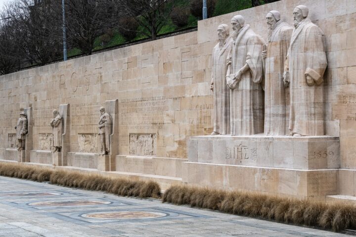 The four central reformers rise beside inscriptions and smaller statues along the Reformation Wall in Geneva's Parc des Bastions.