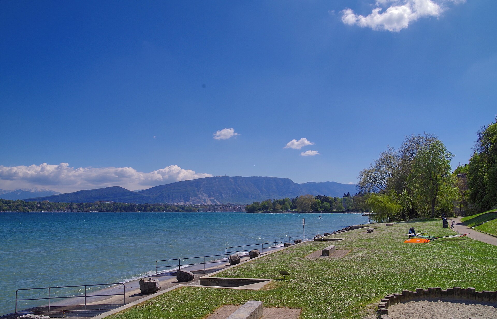 A sunny lawn running down to the shore of Lake Geneva at the Reposoir in Pregny-Chambésy, with the Salève ridge across the water