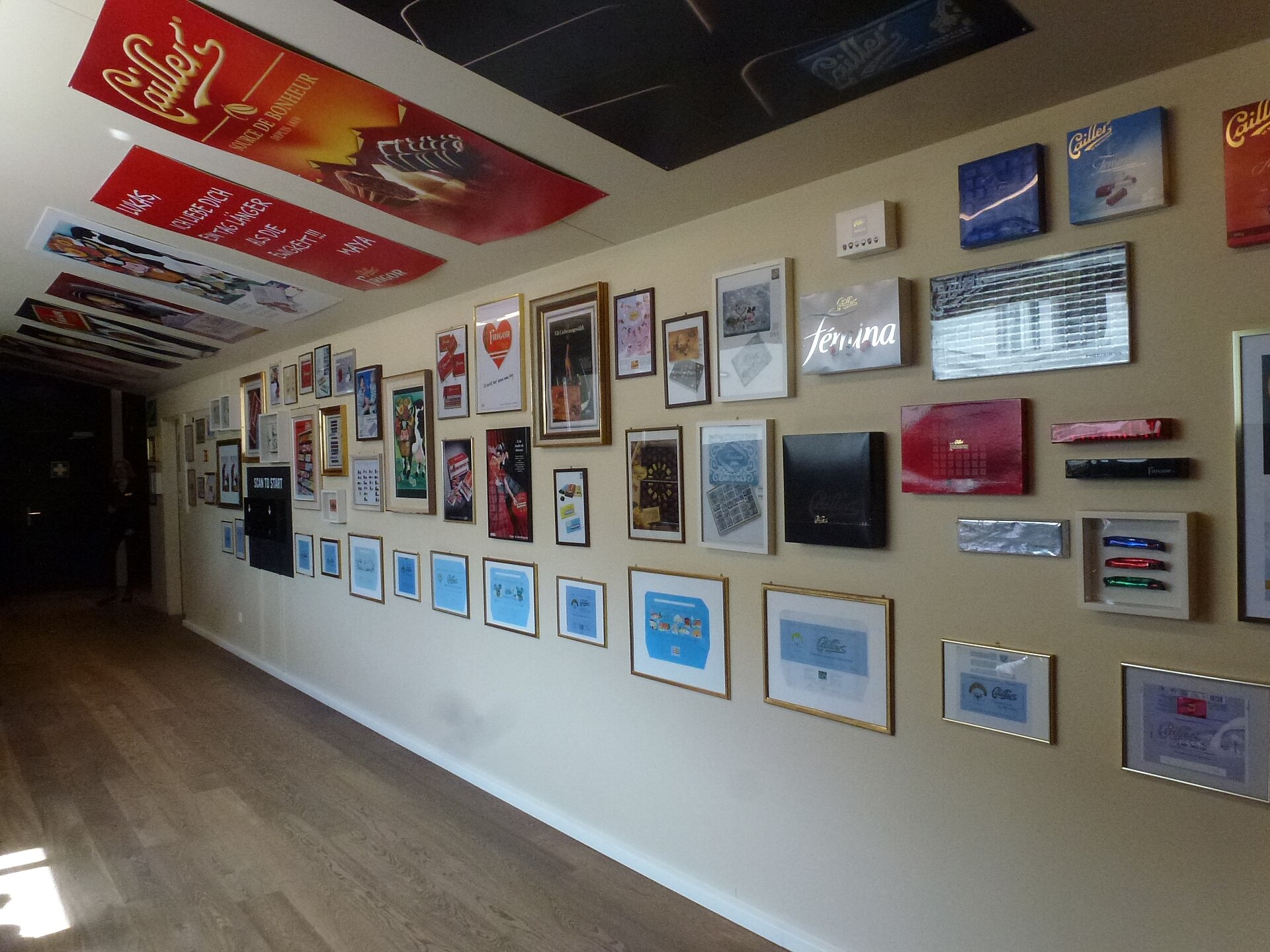 Historic Cailler advertisements and chocolate wrappers line the walls and ceiling of an exhibition corridor at Maison Cailler in Broc.