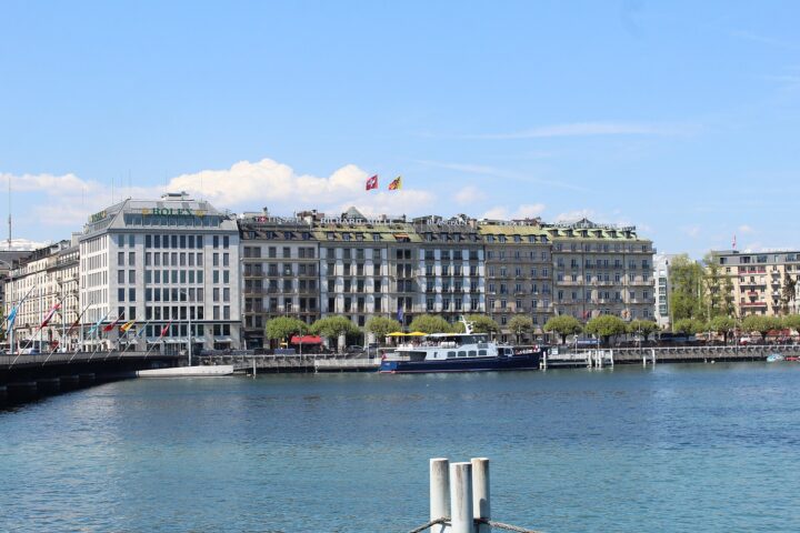 Hôtel de la Paix overlooks Geneva's Quai du Mont-Blanc, with a moored passenger boat and blue lake water in front.