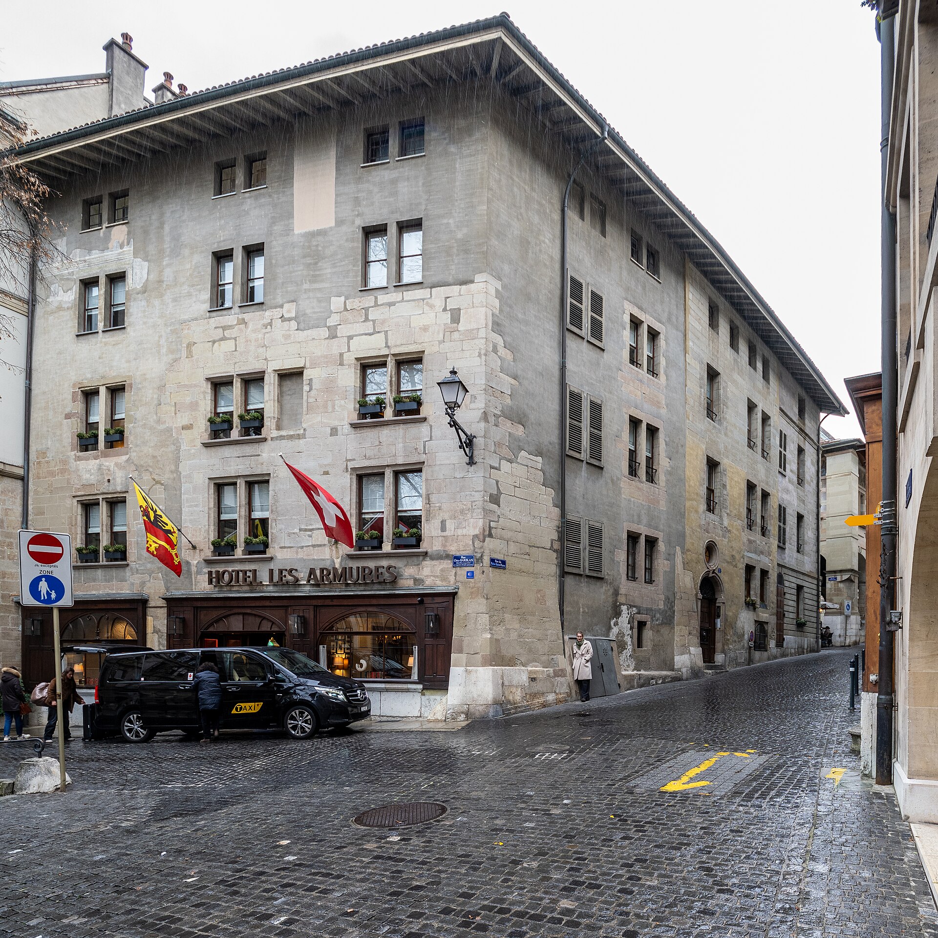 Hotel Les Armures occupies a stone corner building beside cobbled streets in Geneva's Old Town, with flags above its entrance.