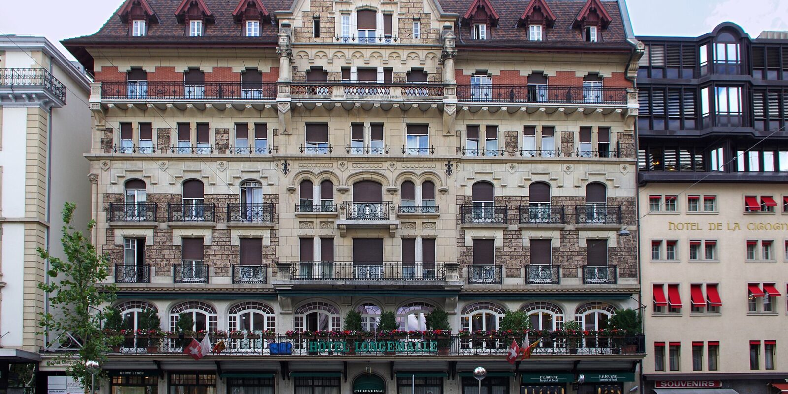 Hotel Longemalle's ornate gabled facade and flowered balconies face the street in Geneva, beside Hôtel de la Cigogne.