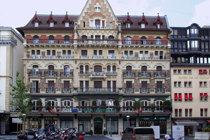 Hotel Longemalle's ornate gabled facade and flowered balconies face the street in Geneva, beside Hôtel de la Cigogne.