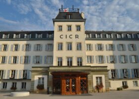 The ICRC headquarters in Geneva displays large CICR letters above its entrance and a Red Cross flag on the roof.