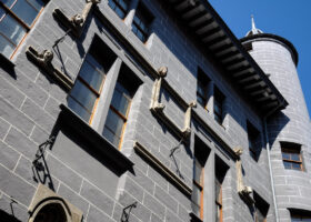 Maison Tavel's carved window surrounds and round corner turret rise against a blue sky in Geneva Old Town.