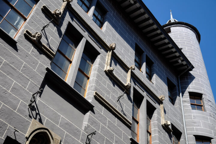 Maison Tavel's carved window surrounds and round corner turret rise against a blue sky in Geneva Old Town.
