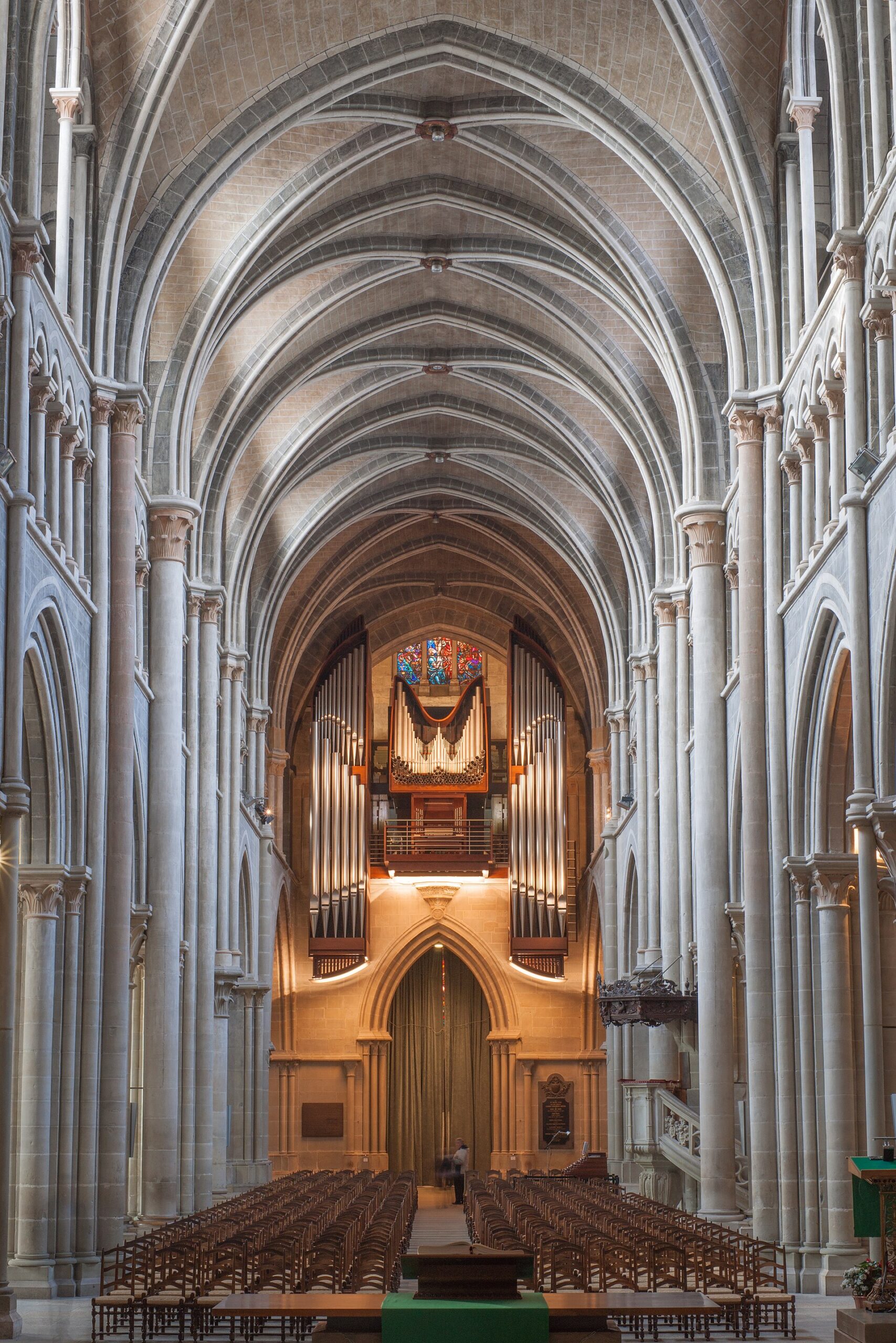 Rows of wooden chairs lead beneath the tall ribbed vaults of Lausanne Cathedral toward its organ and stained glass.