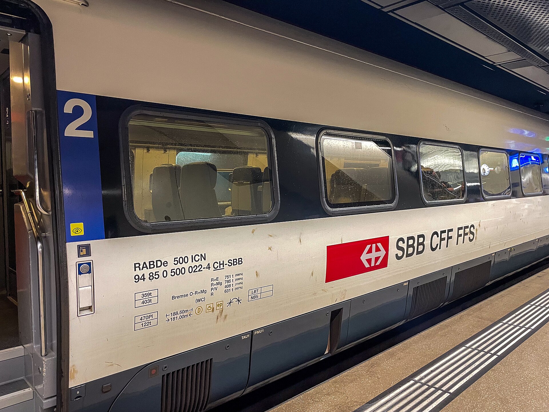 An SBB second-class carriage at Geneva Airport station displays its railway branding beside windows overlooking rows of seats.