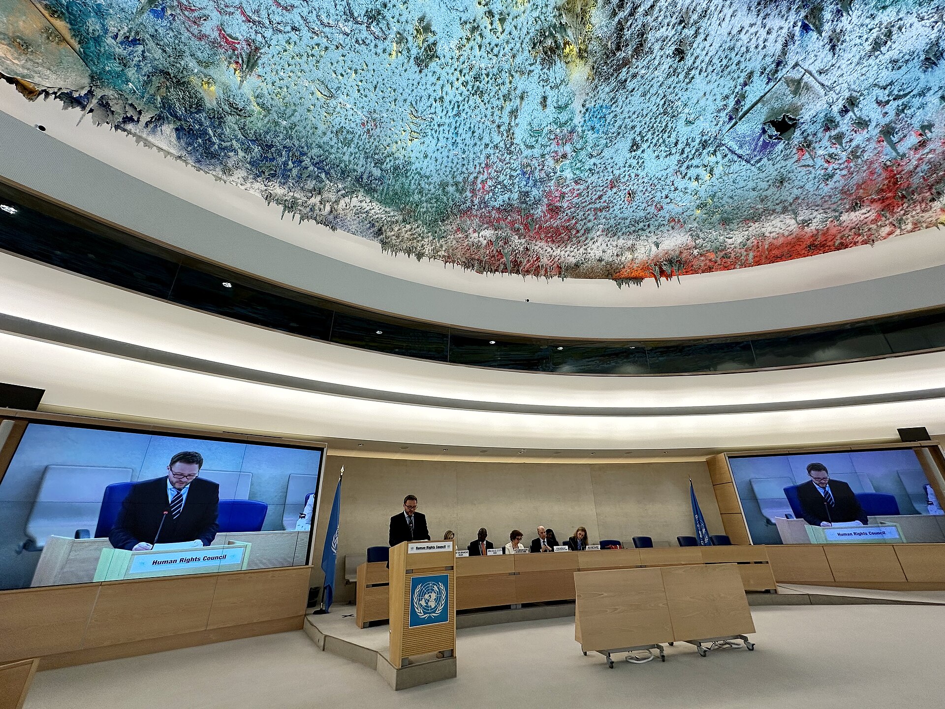 A speaker addresses delegates beneath the multicoloured ceiling of the Human Rights and Alliance of Civilizations Room in Geneva.