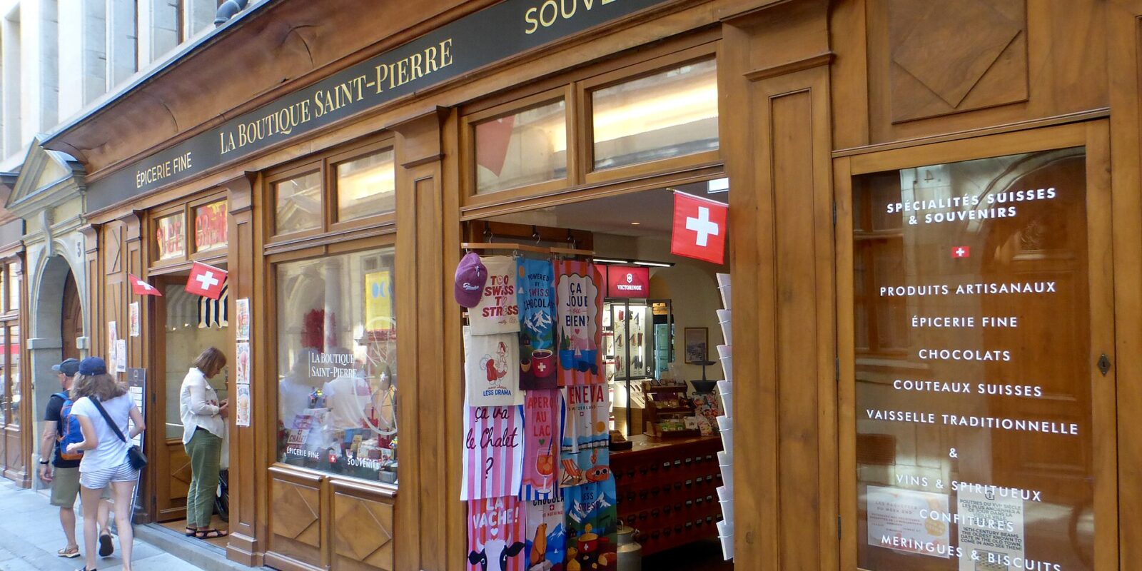 Swiss flags and colorful souvenirs frame the entrance to La Boutique Saint-Pierre on Geneva's Rue de l'Hôtel-de-Ville.