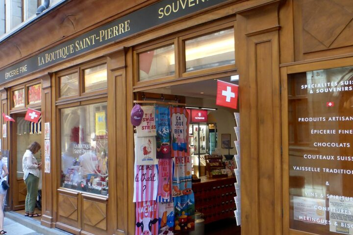 Swiss flags and colorful souvenirs frame the entrance to La Boutique Saint-Pierre on Geneva's Rue de l'Hôtel-de-Ville.