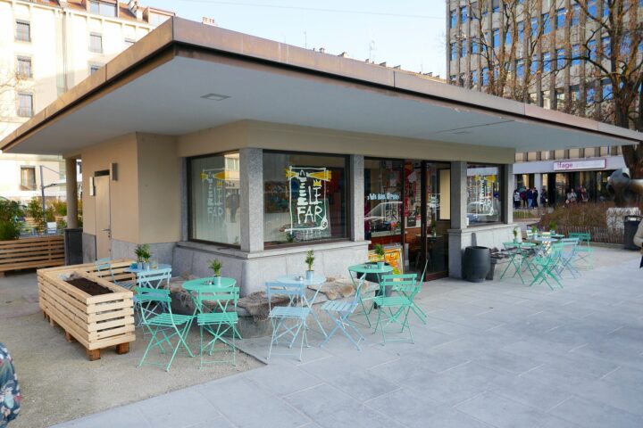Turquoise tables and folding chairs surround the restaurant kiosk at Place des Augustins in Geneva.