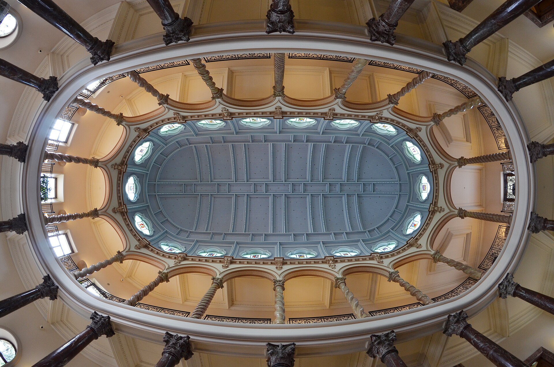 Twisted columns and stained-glass windows surround the oval vaulted ceiling of the Ariana museum hall in Geneva.
