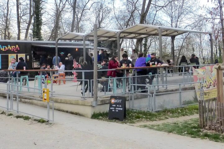 Visitors gather at the Sadara restaurant terrace among trees in Geneva's Bois de la Bâtie.