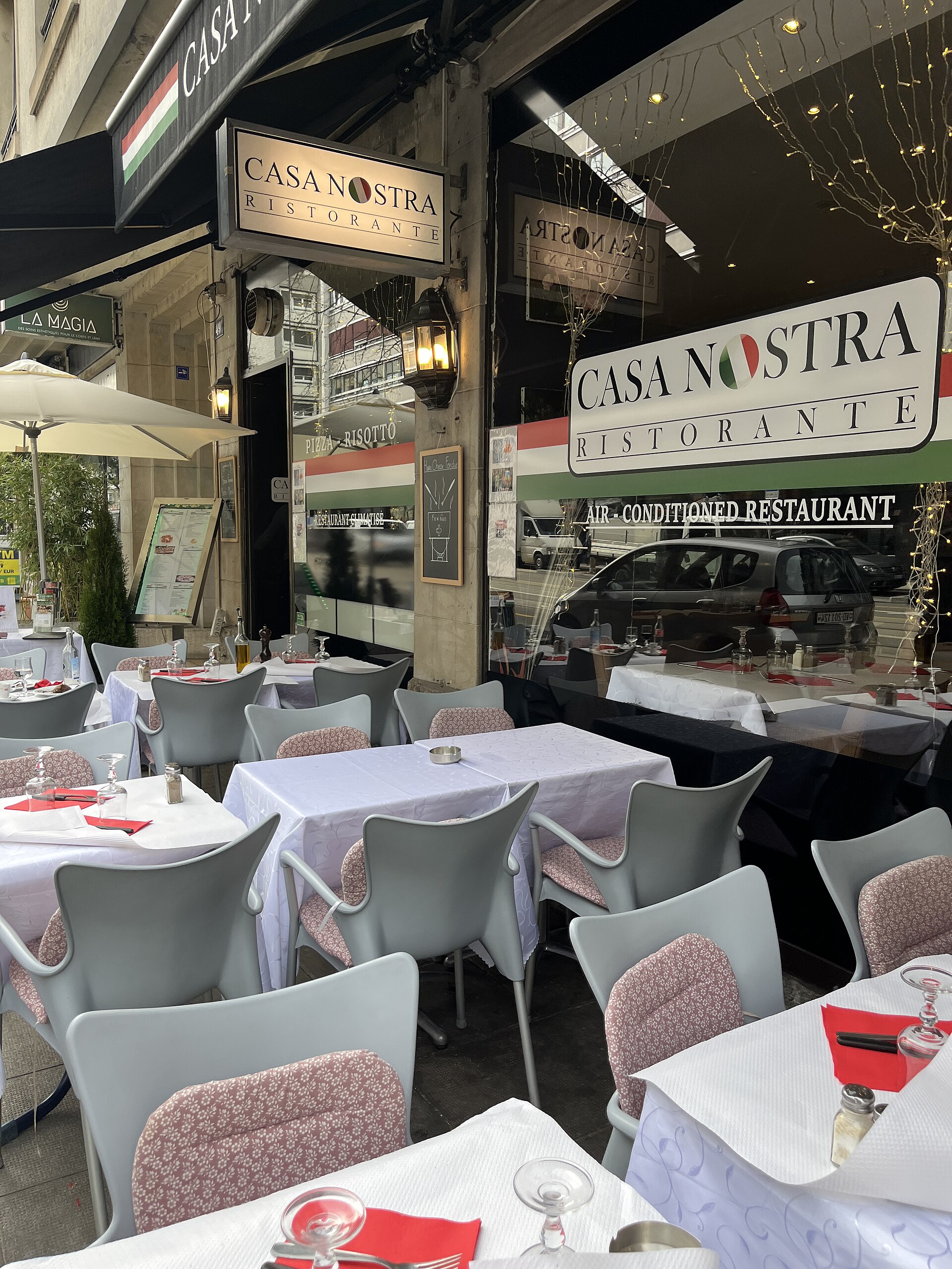 White tablecloths, red napkins and wine glasses cover terrace tables outside Casa Nostra on Rue de Lausanne in Geneva.