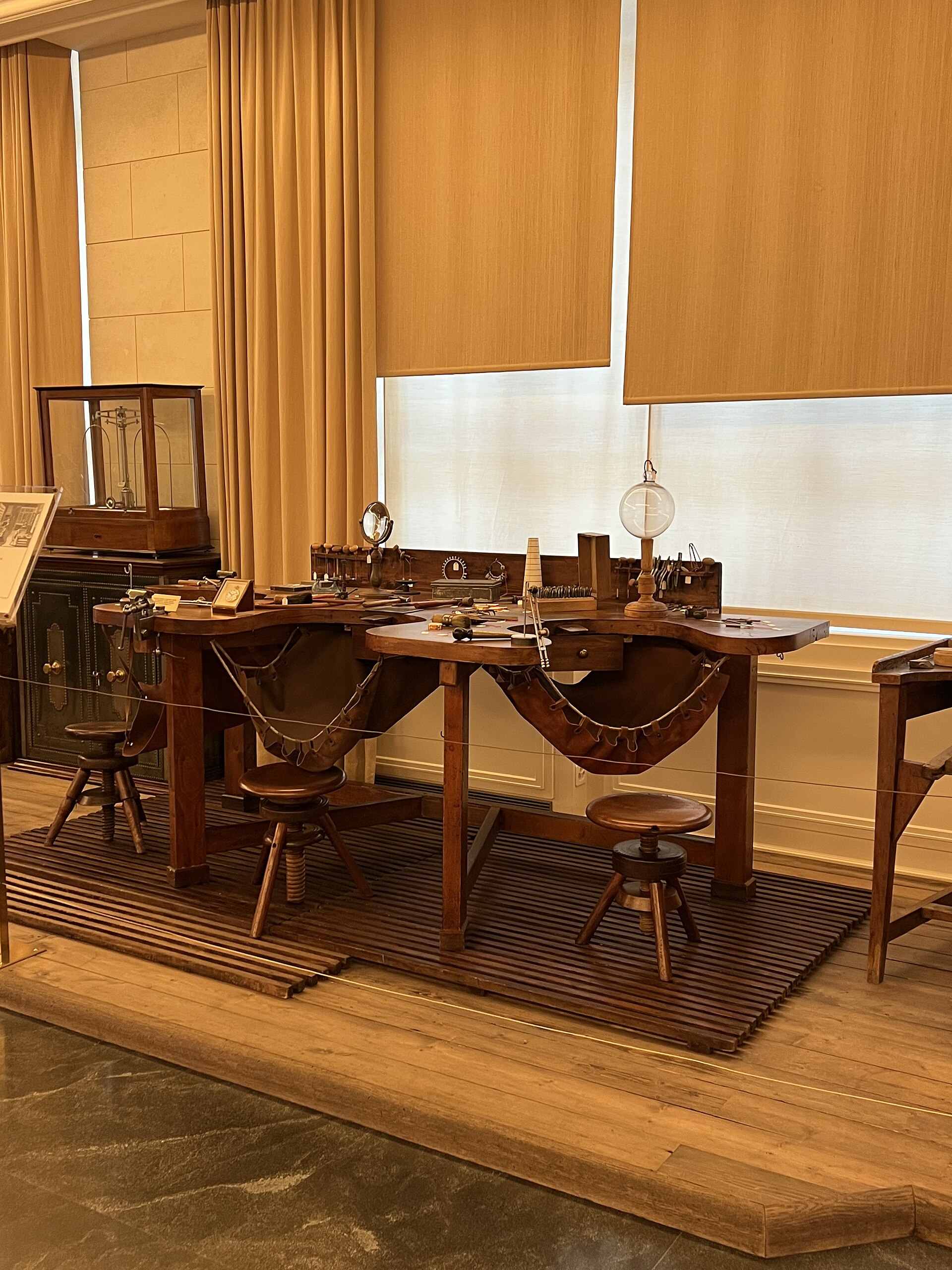 Wooden watchmaking benches, stools and small tools form a roped-off display inside Geneva’s Patek Philippe Museum.