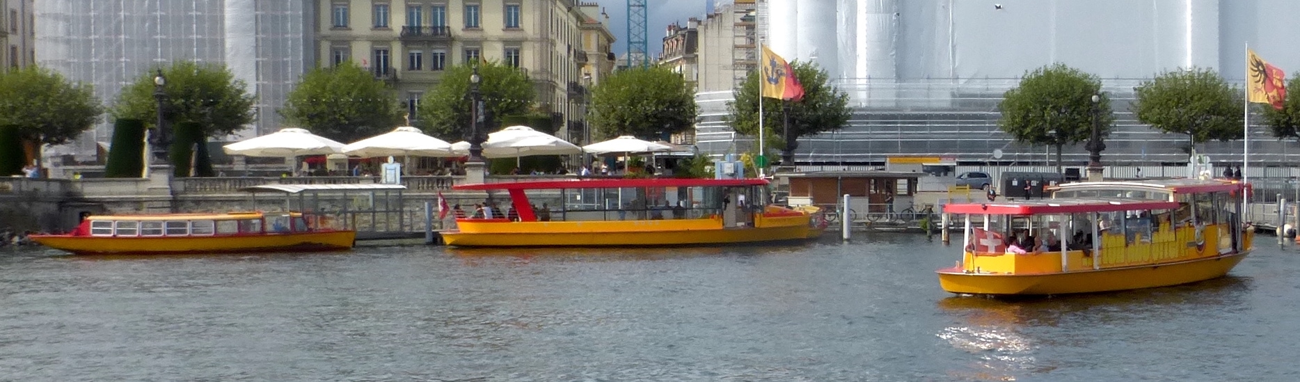 Yellow Mouette carrying passengers off the Pâquis waterfront in Geneva, with two other Mouettes beside the landing.